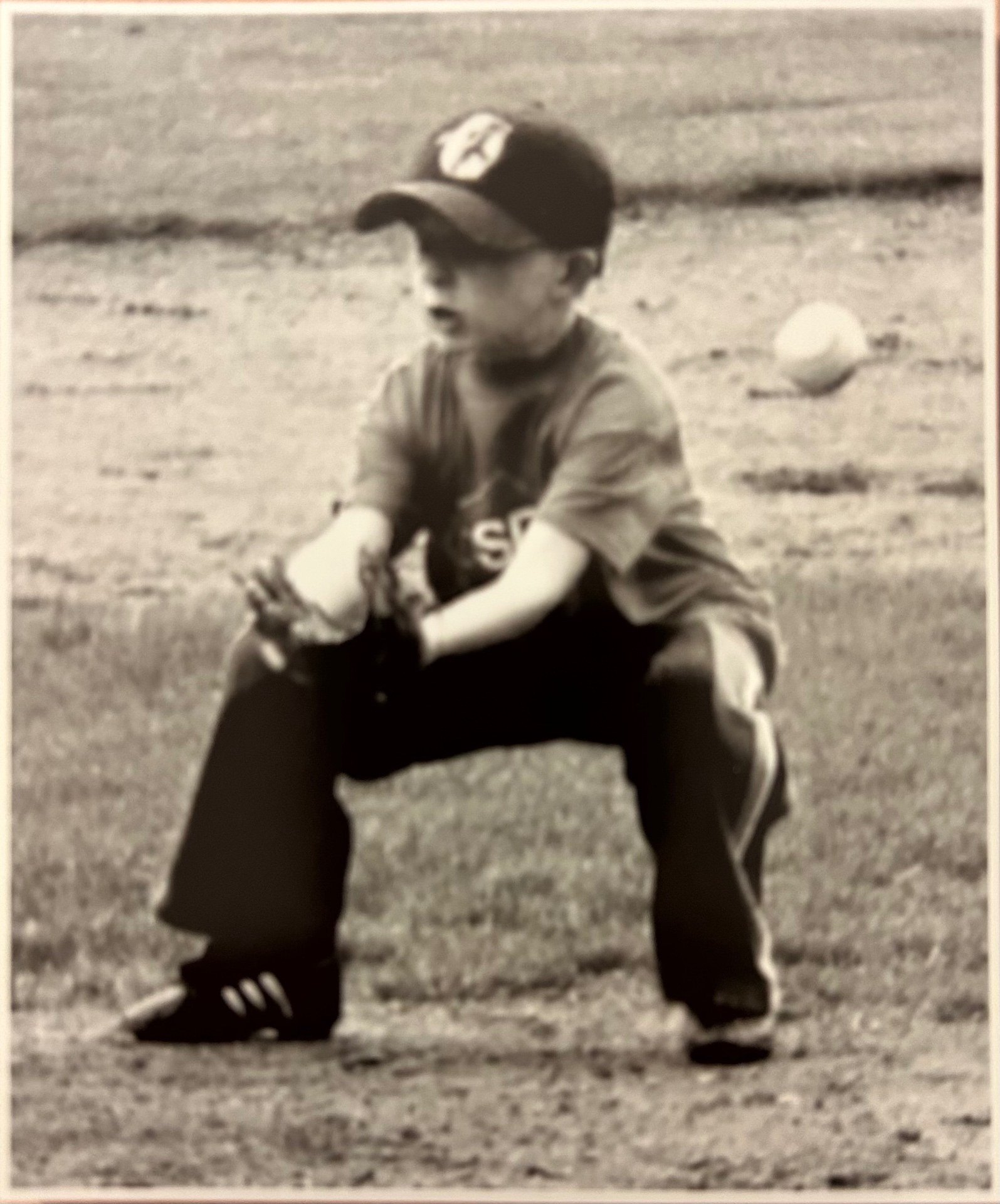 Jack as a young boy in a T-ball uniform, crouched and ready to field a ground ball