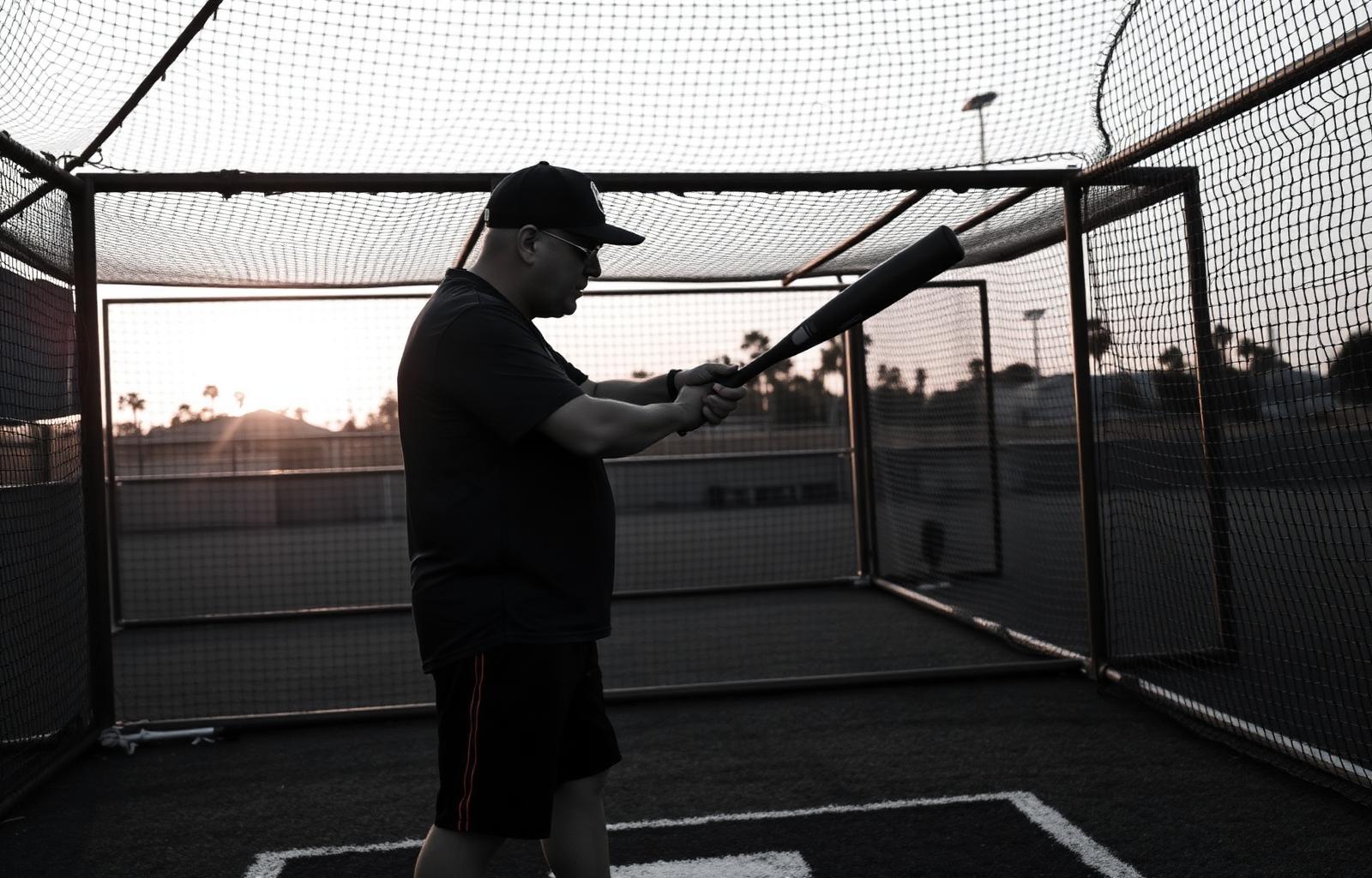 Coach demonstrating batting stance at sunset
